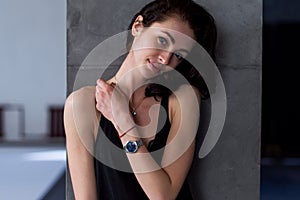 Smiling skinny female model standing at the wall wearing casual clothes