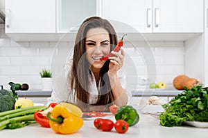 Smiling Skittish Brunette Biting a Chili Pepper Tip photo