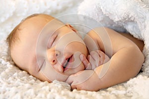 Smiling Sleeping Newborn Baby Girl Wrapped in White Blanket