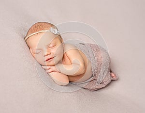 Smiling sleeping newborn girl covered with shawl