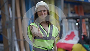 Smiling slim beautiful Caucasian woman in hard hat stretching hand for greeting looking at camera standing in industrial