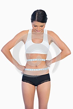 Smiling slim woman measuring her waist
