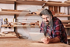 Smiling small business owner in woodwork studio with digital tab photo