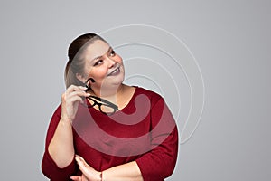 Smiling smart obese lady with eyeglasses looking away in studio