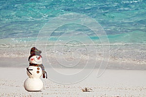 Smiling snowman with and small crab relaxing on tropical beach. New Years and Christmas holidays in hot countries concept