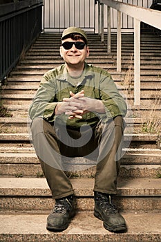 Smiling soldier in sunglasses on stairs