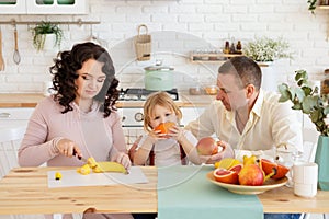 Smiling son eating orange with parents