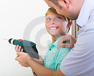 Smiling son helping proud father to drill