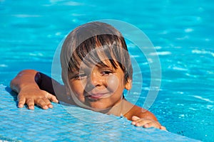 Smiling soppy boy looking happily in swimming pool