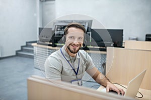 Smiling specialist in headphones behind laptop