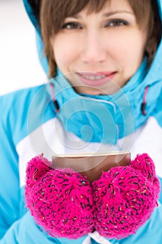 Smiling sport woman holding cup of hot tea or coffee