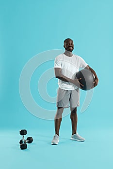 Smiling sports man in sports wear with med ball on background