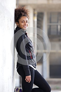 Smiling sports woman relaxing leaning against wall