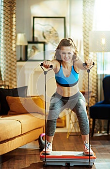 Smiling sports woman training using vibration power plate