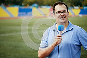 Smiling sportscaster with microphone is reporting photo