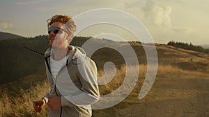 Smiling sportsman running on mountain road. Male athlete jogging outdoor