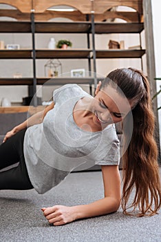 Smiling sportswoman doing side plank exercise