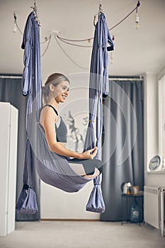 Smiling sportswoman doing a yoga exercise in a hammock