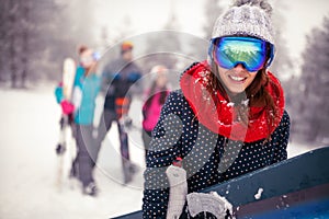 Smiling sporty female holds snowboard in mountains on winter