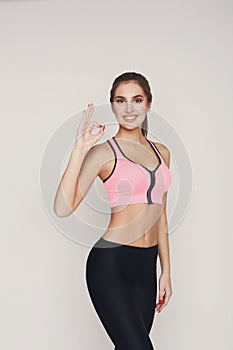 Smiling sporty woman gesturing ok sign