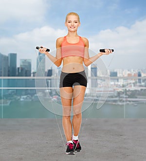 Smiling sporty woman jumping with skipping rope