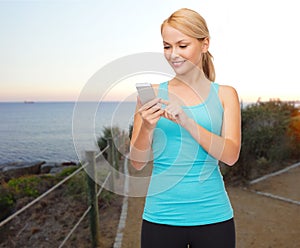 Smiling sporty woman with smartphone outdoors