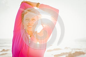 Smiling sporty woman stretching arms at promenade