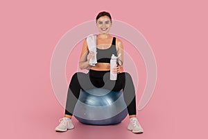 Smiling sporty woman taking break after training on blue fitness ball