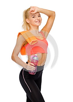 Smiling sporty woman with towel and water bottle