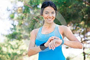 Smiling sporty woman using smart watch outdoors