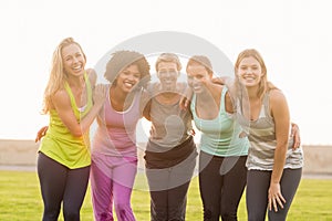 Smiling sporty women with arms around each other