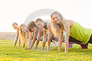 Smiling sporty women doing push ups during fitness class