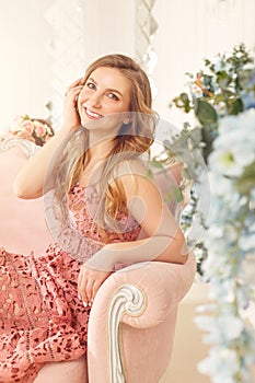 Smiling spring girl in a pink dress on a sunny terrace