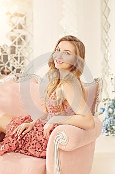 Smiling spring girl in a pink dress on a sunny terrace