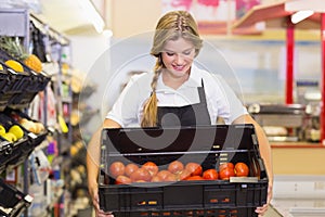 Smiling staff woman holding a box with fresh tomatos