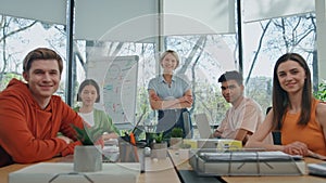 Smiling startupers looking camera modern cabinet. Five people sitting together