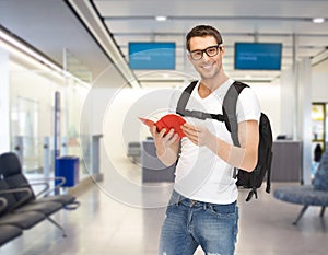 Smiling student with backpack and book at airport