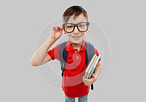 Smiling student boy in glasses with books and bag