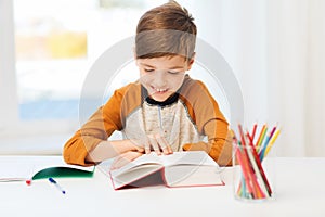 Smiling, student boy reading book at home