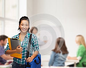 Smiling student with folders, tablet pc and bag