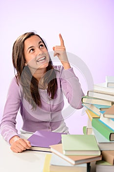 Smiling student girl pointing up purple background