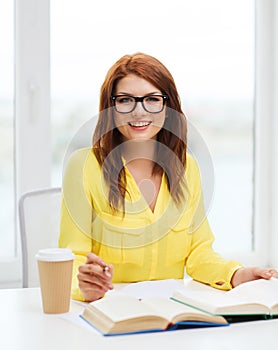 Smiling student girl reading books in library