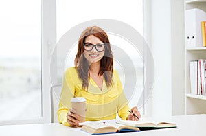 Smiling student girl reading books in library