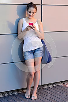 Smiling student girl using mobile phone college