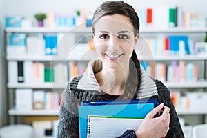 Smiling student holding notebooks