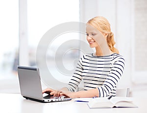 Smiling student with laptop computer and notebook