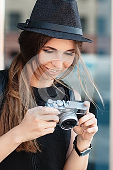 The smiling student photographs with digital mirrorless camera.