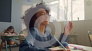 Smiling student raising hand at lesson. Laughing schoolgirl answering question