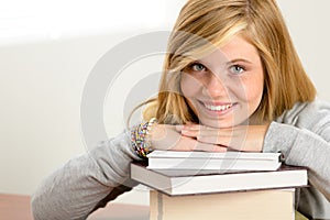 Smiling student teenager leaning head on books