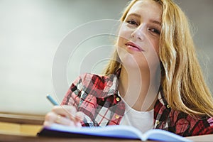 Smiling student writing on notebok photo